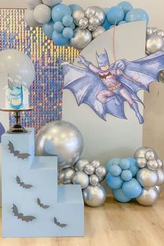 balloons and decorations are arranged on the floor in front of a wall with an image of batman