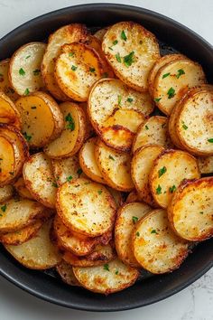 cooked potatoes with parsley in a skillet on a white counter top, ready to be eaten