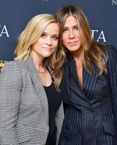 two women standing next to each other on a red carpet