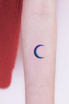 a woman's arm with a small crescent tattoo on the left side of her arm