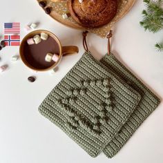 two crocheted coasters sitting on top of a table next to a cup of coffee