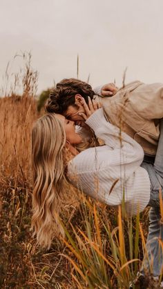 a man and woman kissing in the middle of tall grass with their heads close to each other