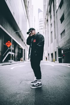 a man standing in the middle of an empty street with his hand on his face