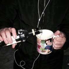 a man is holding a cup with headphones on