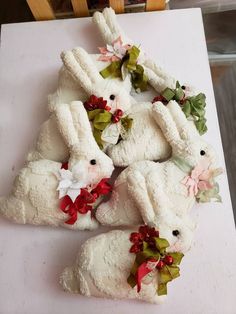 several white stuffed animals sitting on top of a wooden table with red and green bows