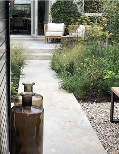 an outside view of a house with flowers and plants in the front yard, along with two vases