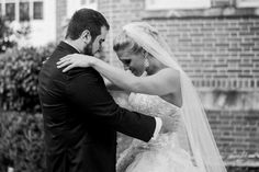 a bride and groom embracing each other in front of a brick building on their wedding day