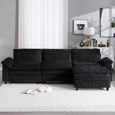 a living room with a black couch and white rug