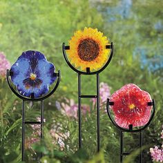 three sunflowers and one flower are in the middle of some metal stands with flowers on them