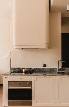 a kitchen with white cabinets and marble counter tops, along with stainless steel ovens