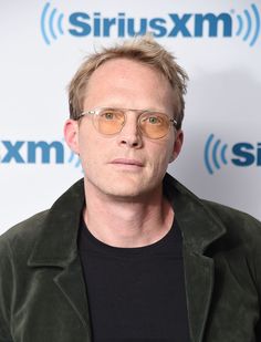 a man with glasses and a black shirt is standing in front of an sirius logo