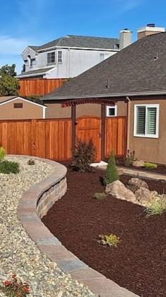 a house with a wooden fence next to it and landscaping in front of the house