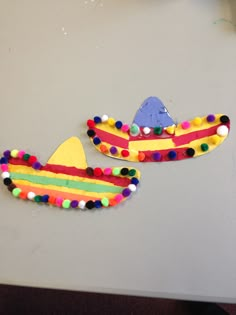 two paper mache shaped like boats on top of a white table with pom - poms