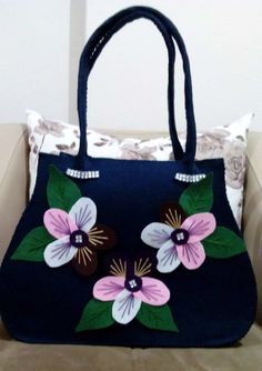 a handbag with flowers painted on it sitting on a couch next to a pillow