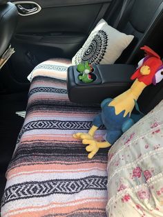 stuffed animals are sitting on the back seat of a car, next to pillows and blankets