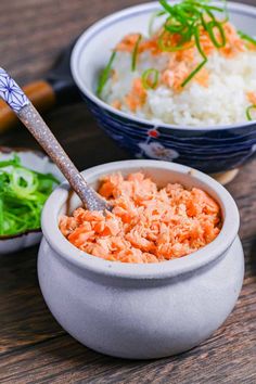 two bowls filled with rice and carrots on top of a wooden table next to chopsticks