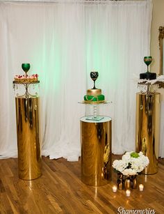 three gold pedestals with green and white cakes on them in front of a curtain