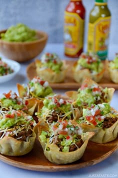 some taco cups are sitting on a plate with guacamole and salsa