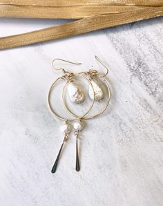 Embrace the carefree beachy boho vibe with these stunning gold hoops. Featuring a fresh water pearl nugget suspended at the center, these earrings are accented with a 1 1/2 inch chain adorned with delicate moonstone gemstones. A unique blend of pearl and moonstone, these earrings are perfect for adding a touch of coastal elegance to any outfit. All materials are gold filled. Approximately 2 1/4 inches in length. Brass Dangle Jewelry With Pearl Charm, Everyday Metal Pearl Drop Jewelry, Everyday Metal Jewelry With Pearl Drop, Brass Pearl Drop Dangle Jewelry, Brass Dangle Pearl Drop Jewelry, Adjustable Small Hoop Pearl Drop Jewelry, Adjustable Pearl Charm Drop Earrings, Pearl Drop Dangle Jewelry, Bohemian Teardrop Pearl Jewelry