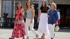 four women are walking down the street together