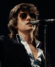 a man with sunglasses on singing into a microphone