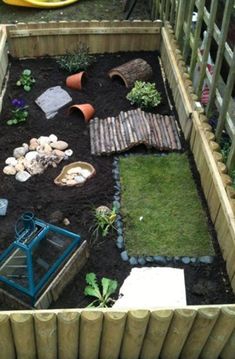 a small garden with rocks and plants in the middle, surrounded by wooden fence posts