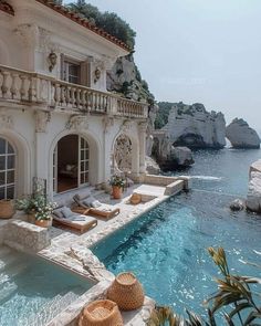 an outdoor swimming pool with chaise lounges next to the water and cliffs in the background