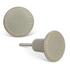 pair of round studs with gold dots on grey surface, set against white background