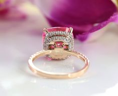 a diamond and pink tourmaline ring sitting on top of a flower