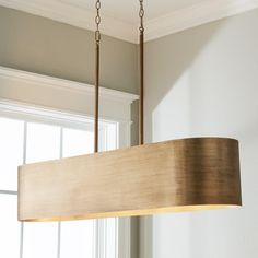 a wooden light fixture hanging from a ceiling in a room with white walls and windows