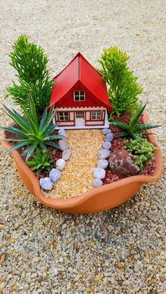 a miniature house in a planter filled with rocks and plants on top of gravel