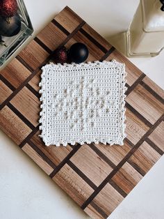 a wooden cutting board topped with a white crochet dishcloth