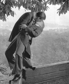 a man in a suit and tie kissing another man on the side of a hill