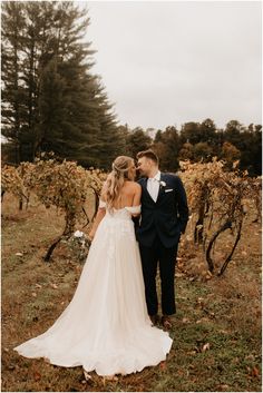 a bride and groom standing in front of some vines