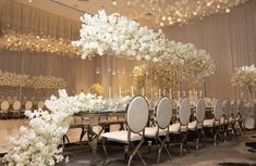 an elegant dining room with white flowers and chandelier hanging from the ceiling,