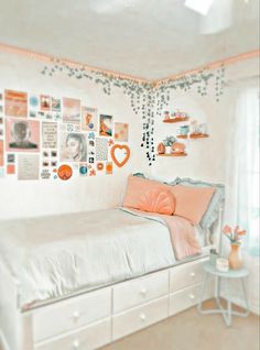 a bedroom with white walls and pictures on the wall above the bed, along with an orange throw pillow