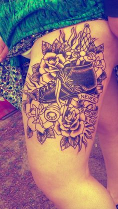 a woman's thigh with a tattoo on it and flowers around the leg,