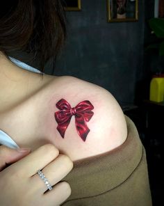 a woman with a red bow tattoo on her shoulder