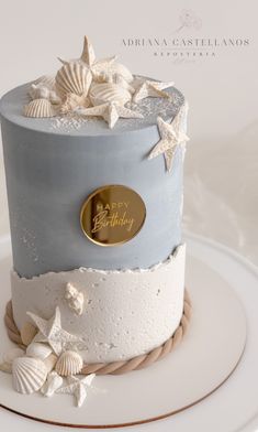 a blue and white cake with seashells on it