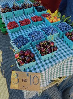 an outdoor fruit stand with blue and white checkered tablecloths, baskets filled with fresh berries