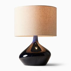 a black and brown table lamp with a beige shade on it's side, against a white background