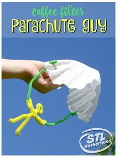 a hand holding a white paper bag with green string attached to it and the words coffee filter parachute guy