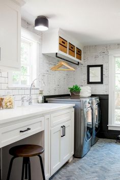 a kitchen with white cabinets and black counter tops, an island in the middle is next to a washer and dryer