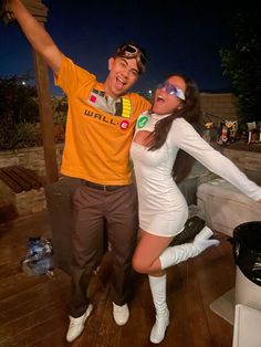 a man and woman posing for a photo in front of a trash can at night