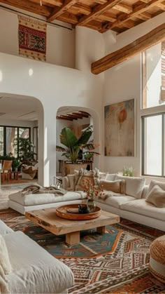 a living room filled with lots of furniture and large windows on the side of it