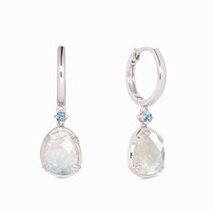 Our elegant silver drop earrings feature organically-shaped rainbow moonstones with brilliant blue cubic zirconia accents.

Thanks to their ethereal blue and white tones, these moonstone dangle earrings are truly one-of-a-kind!

The rainbow moonstones measure at 10mm x 8mm and cubic zirconia stone measure at 2.5mm.

Inner earring diameter measures at 10.5mm. Ethereal Blue, Gem Earrings, Moonstone Earrings, Blue Gems, Sustainable Jewelry, Traditional Jewelry, Silver Drop Earrings, Recycled Sterling Silver, High Quality Jewelry