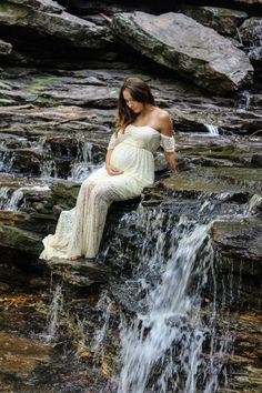 a pregnant woman sitting on top of a waterfall