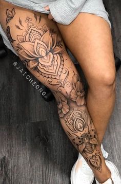 a woman sitting on the floor with her legs crossed and tattoos on her leg,