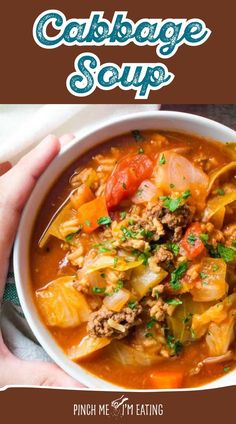 a person holding a bowl of cabbage soup with meat and veggies in it