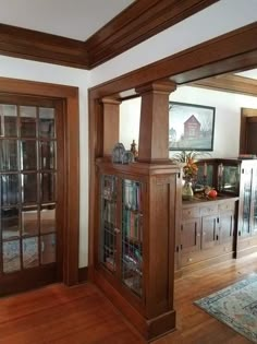 a living room with wood floors and wooden bookcases on the wall next to glass doors